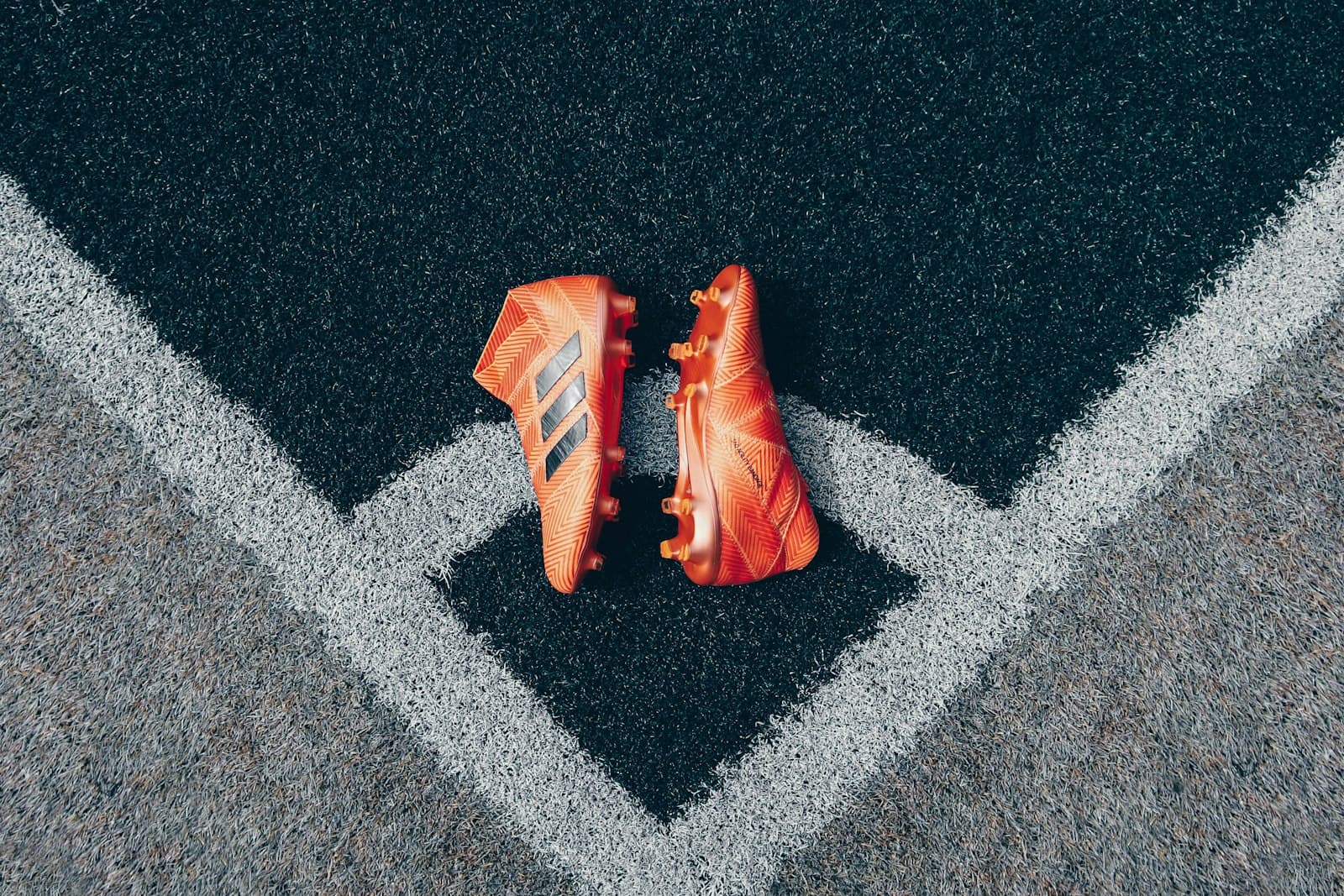 Orange soccer cleats on a gray surface